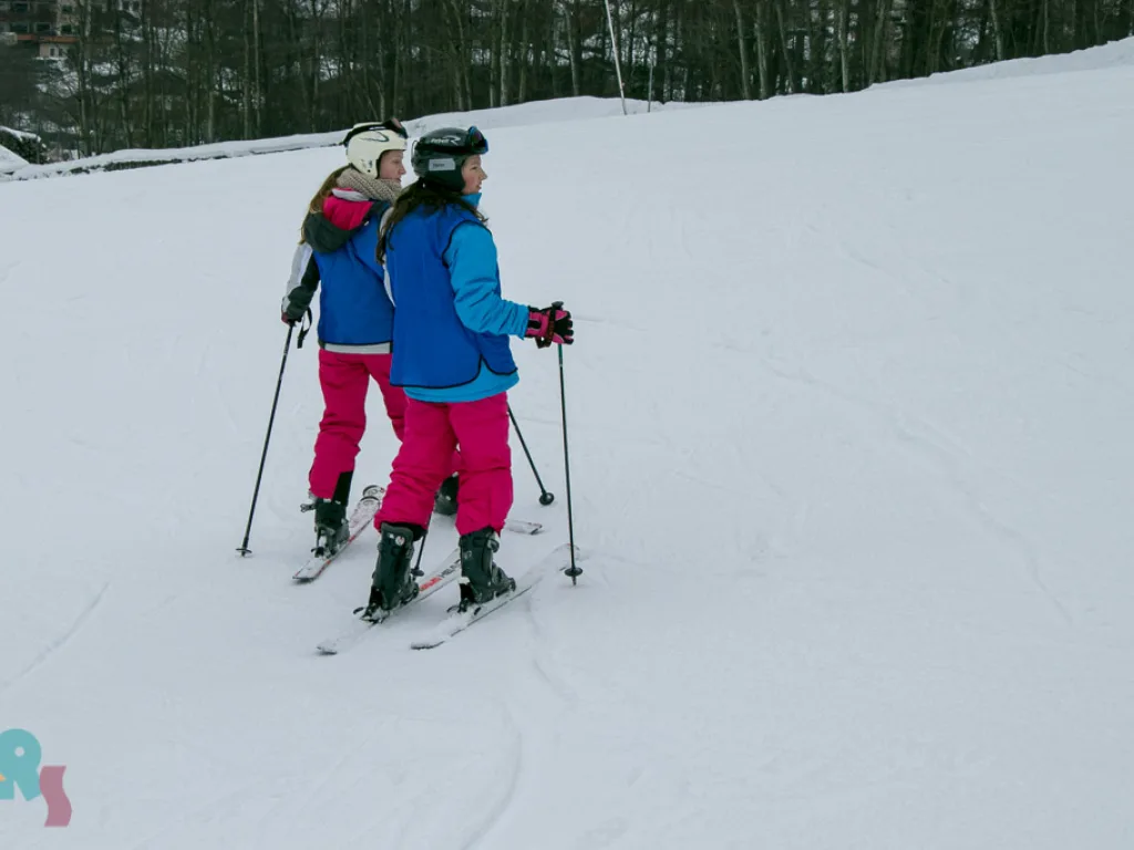 Zwei Skifahrerinnen stehen nebeneinander auf der Piste.
